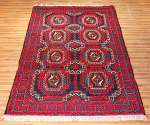 Baluchi Persian runner rug with repeating octagonal tribal medallions on dark red field
