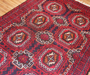 Detailed view of Baluchi Persian rug field with traditional tribal motifs in red, navy and ivory
