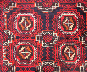 Border detail of hand knotted Baluchi rug with angular tribal guard stripes and geometric pattern

