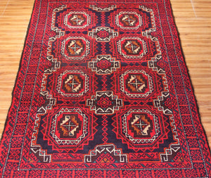Close-up of vintage Baluchi rug showing detailed octagonal guls and navy geometric accents
