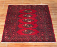 Turkmen Persian rug with repeating diamond gul medallions on vibrant red field
