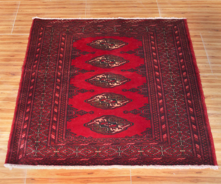 Turkmen Persian rug with repeating diamond gul medallions on vibrant red field
