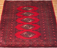 Close-up of vintage Turkmen rug showing detailed tribal guls and dark border motifs

