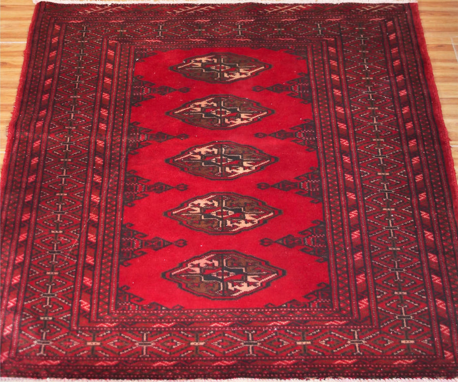 Close-up of vintage Turkmen rug showing detailed tribal guls and dark border motifs

