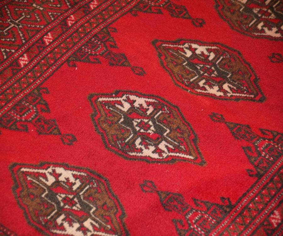 Detailed view of Turkmen Persian rug field with traditional geometric medallions in red, brown and ivory tones