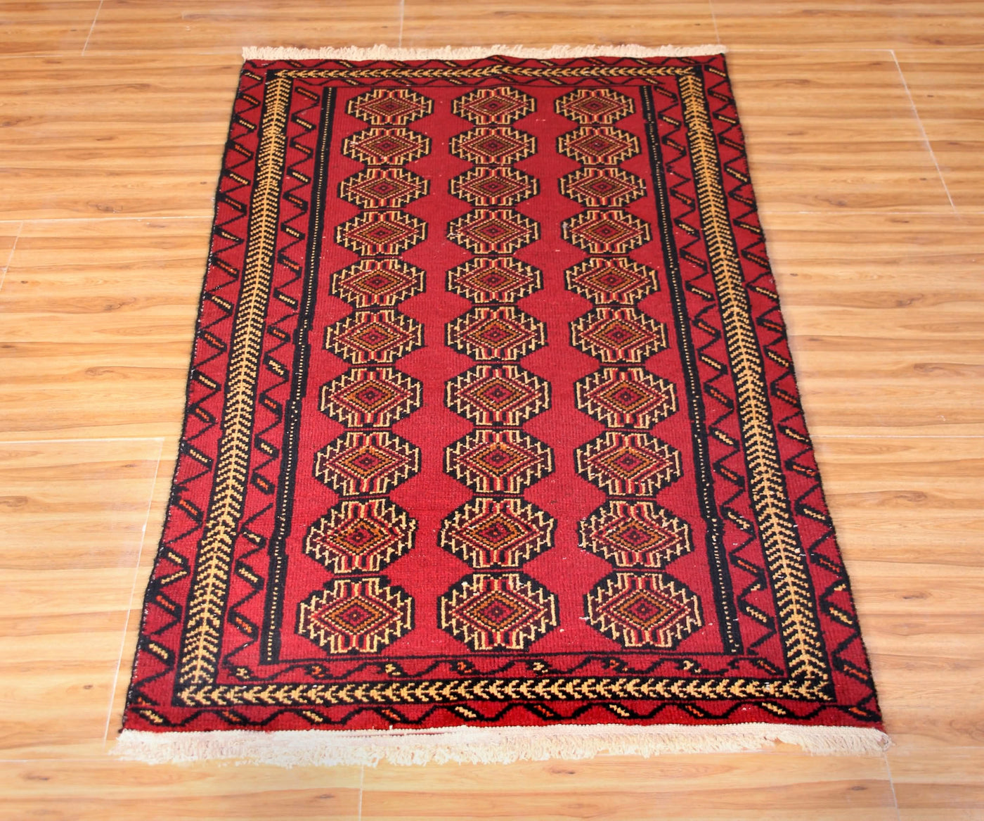 Vintage Turkmen Persian runner full view showing repeating geometric medallions on deep red field
