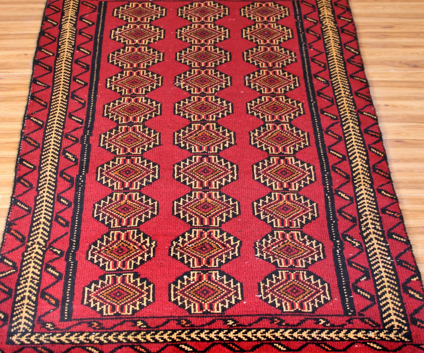 Close-up of Turkmen Persian rug showing detailed repeating gul motifs and intricate borders
