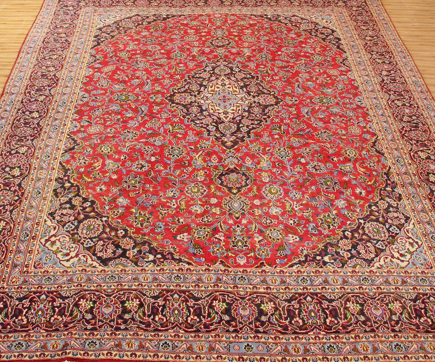 Vintage Mashad rug with grand medallion design and dense floral motifs in red, navy and ivory tones
