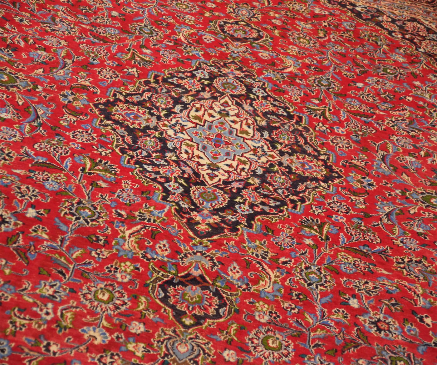 Detailed view of Mashad rug field highlighting rich red background and elaborate floral vines
