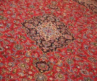 Detailed view of Mashad rug field highlighting rich red background and elaborate floral vines
