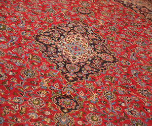 Detailed view of Mashad rug field highlighting rich red background and elaborate floral vines
