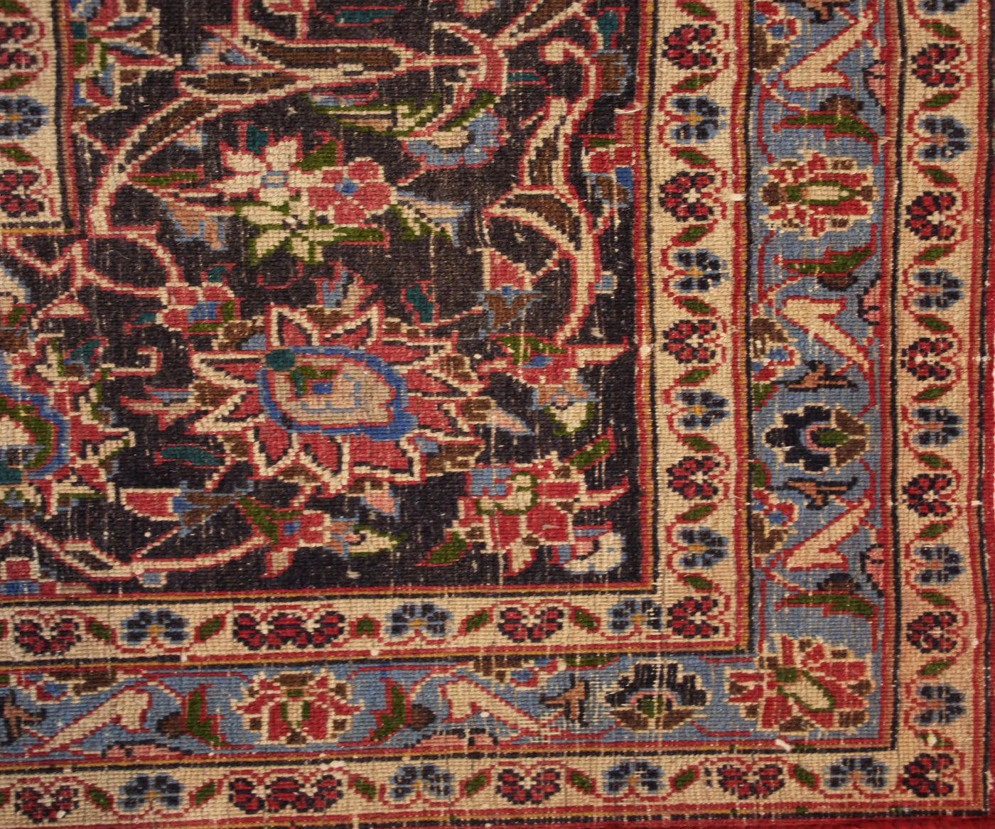 Corner detail of hand knotted Mashad Persian rug showing intricate floral motifs and classic framing border
