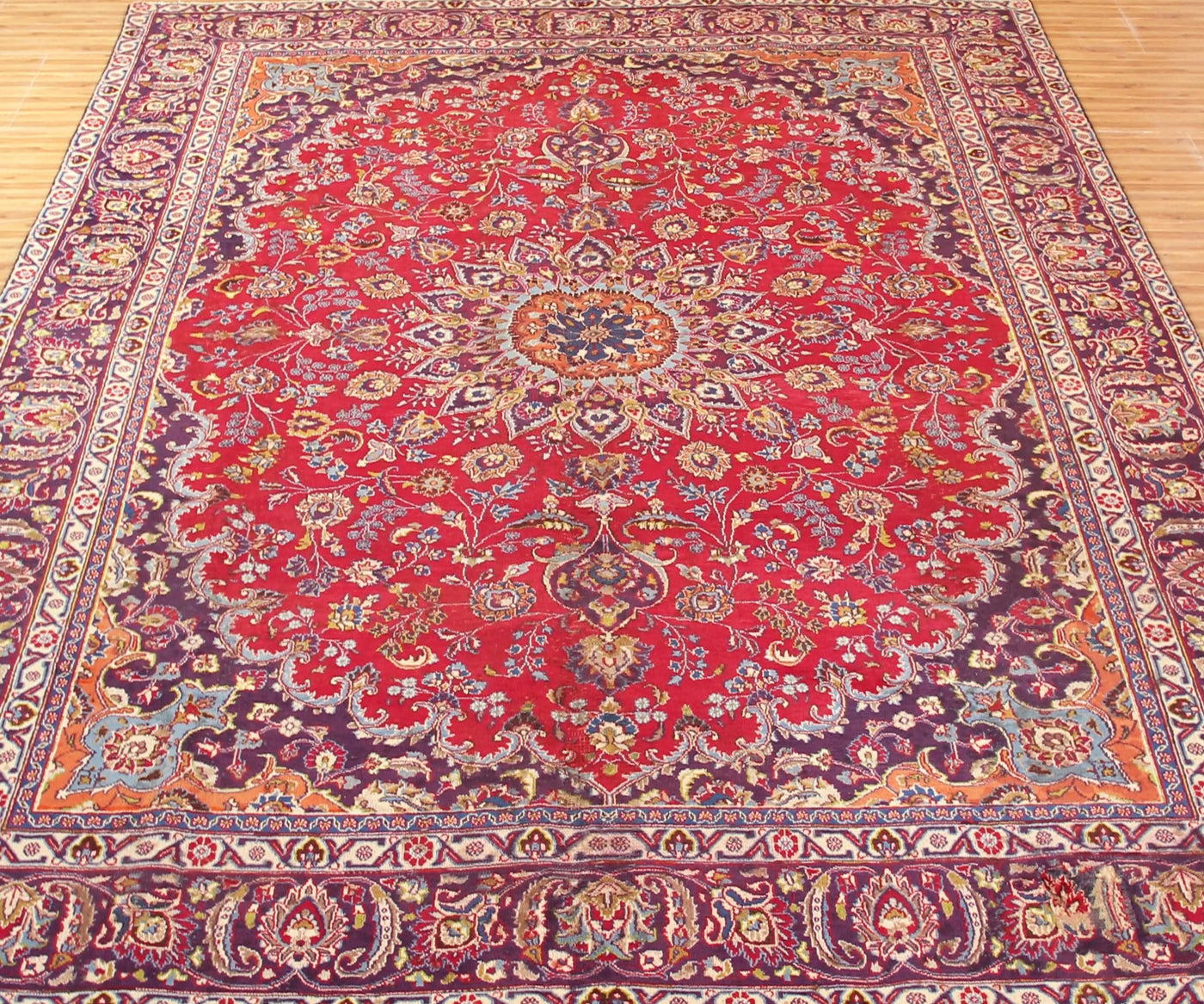 Vintage Mashad rug with elaborate central medallion and dense floral vine motifs in red, navy and ivory tones
