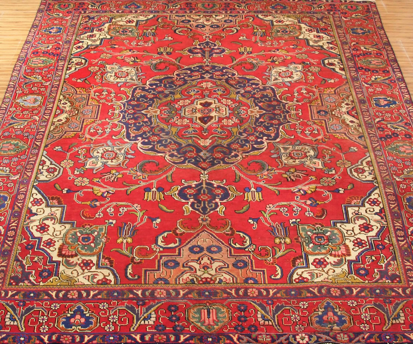 Vintage Tabriz rug featuring elaborate medallion and dense floral arabesque motifs in red, navy and ivory tones
