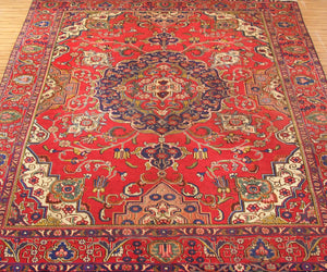 Vintage Tabriz rug featuring elaborate medallion and dense floral arabesque motifs in red, navy and ivory tones
