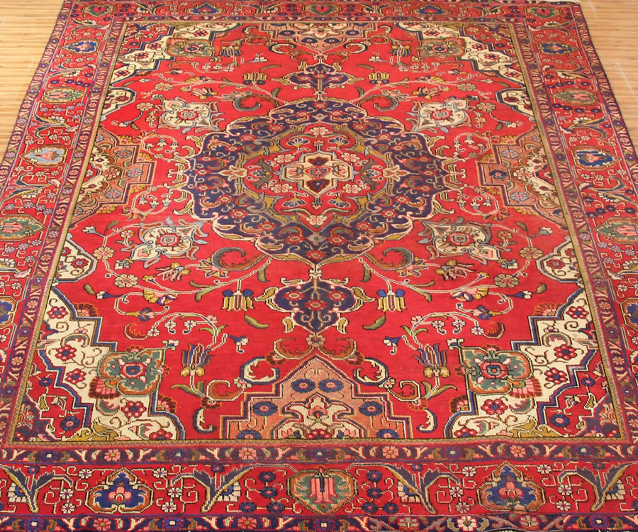 Vintage Tabriz rug featuring elaborate medallion and dense floral arabesque motifs in red, navy and ivory tones
