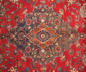 Vintage Mashad rug featuring elaborate medallion and dense floral vine motifs in red, navy and ivory tones
