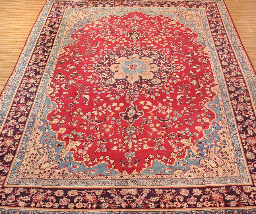 Antique Sabzevar rug featuring elegant central medallion and dense floral vine motifs in red, ivory and blue tones
