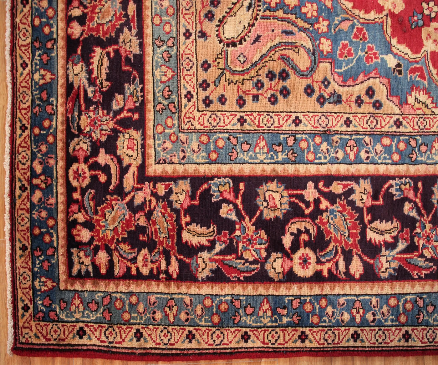 Corner detail of antique Sabzevar Persian rug showing intricate floral motifs and classic framing border
