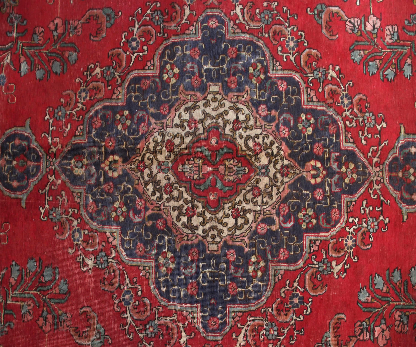 Antique Tabriz rug featuring elaborate medallion and dense floral arabesque motifs in red, navy and ivory tones
