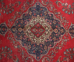 Antique Tabriz rug featuring elaborate medallion and dense floral arabesque motifs in red, navy and ivory tones
