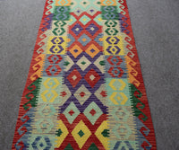 Long tribal kilim runner with repeating geometric medallions and multicolor striped design
