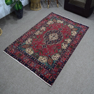 Angled view of hand knotted Shiraz rug highlighting rich red tones and tribal floral motifs