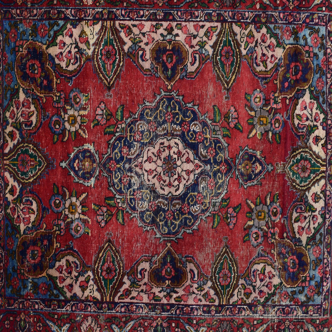 Detailed view of red field with repeating floral motifs surrounding the navy medallion
