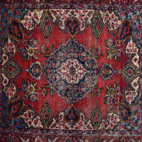 Detailed view of red field with repeating floral motifs surrounding the navy medallion