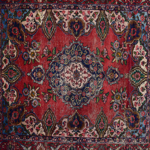 Detailed view of red field with repeating floral motifs surrounding the navy medallion