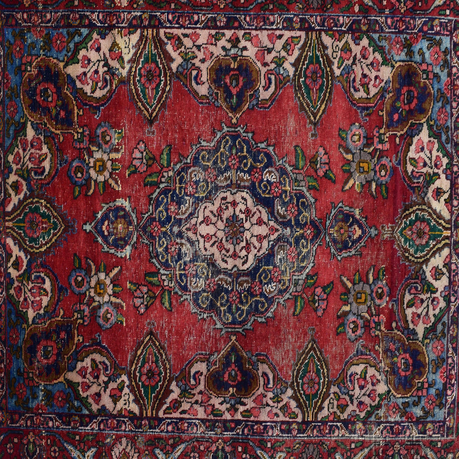 Detailed view of red field with repeating floral motifs surrounding the navy medallion