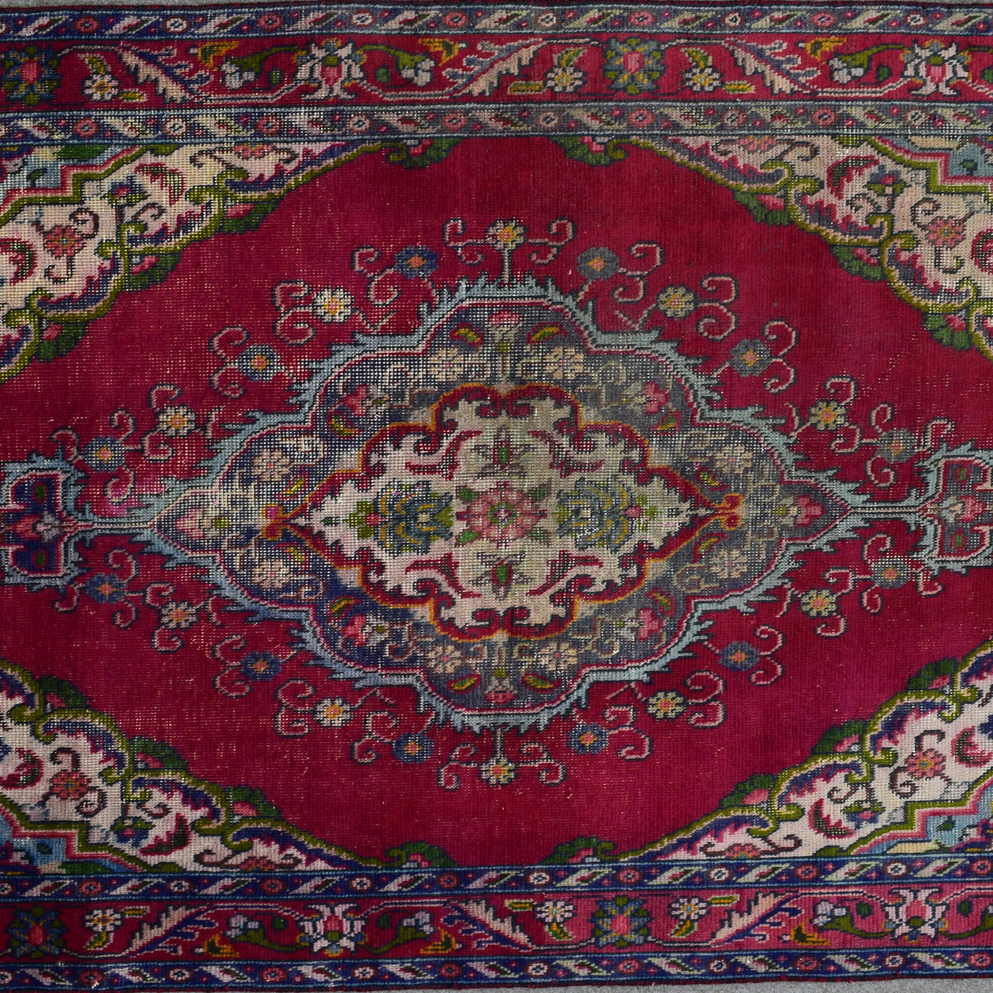 Detailed horizontal view of elongated medallion with scrolling floral motifs on red field