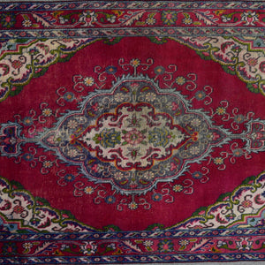 Detailed horizontal view of elongated medallion with scrolling floral motifs on red field