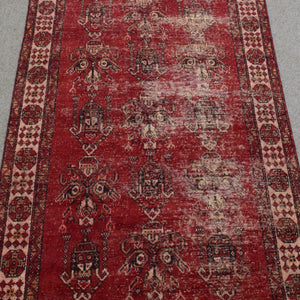 Close-up of rug field showing faded tribal motifs on richly aged red wool