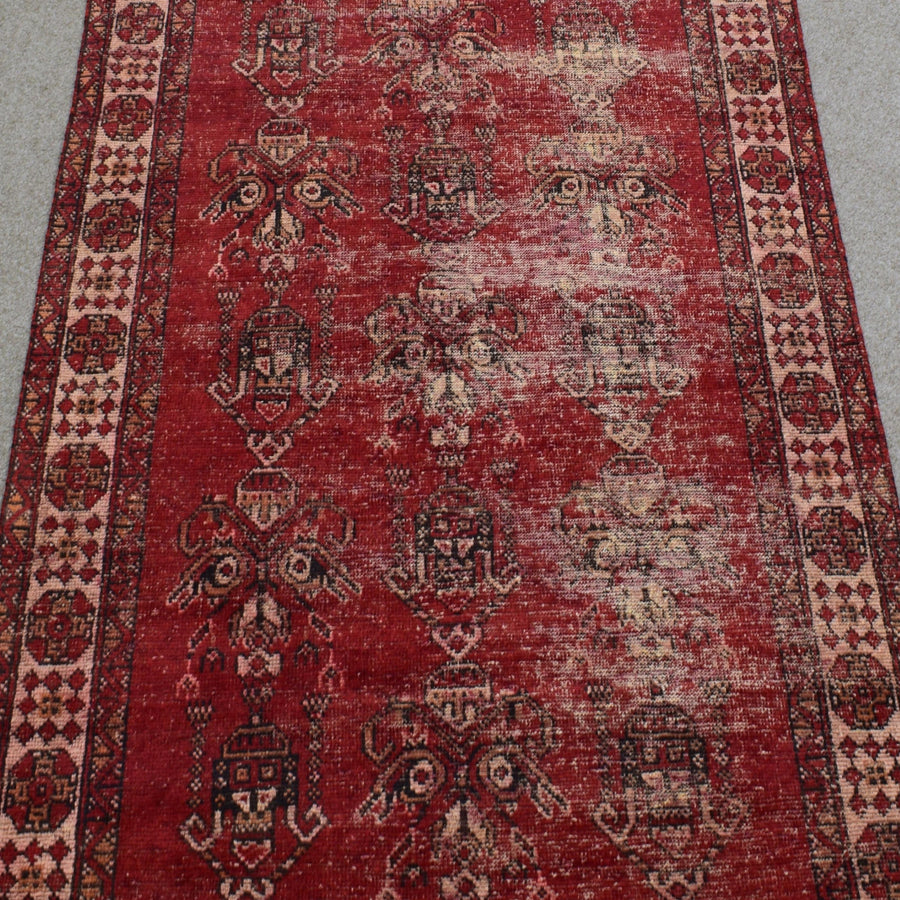 Close-up of rug field showing faded tribal motifs on richly aged red wool