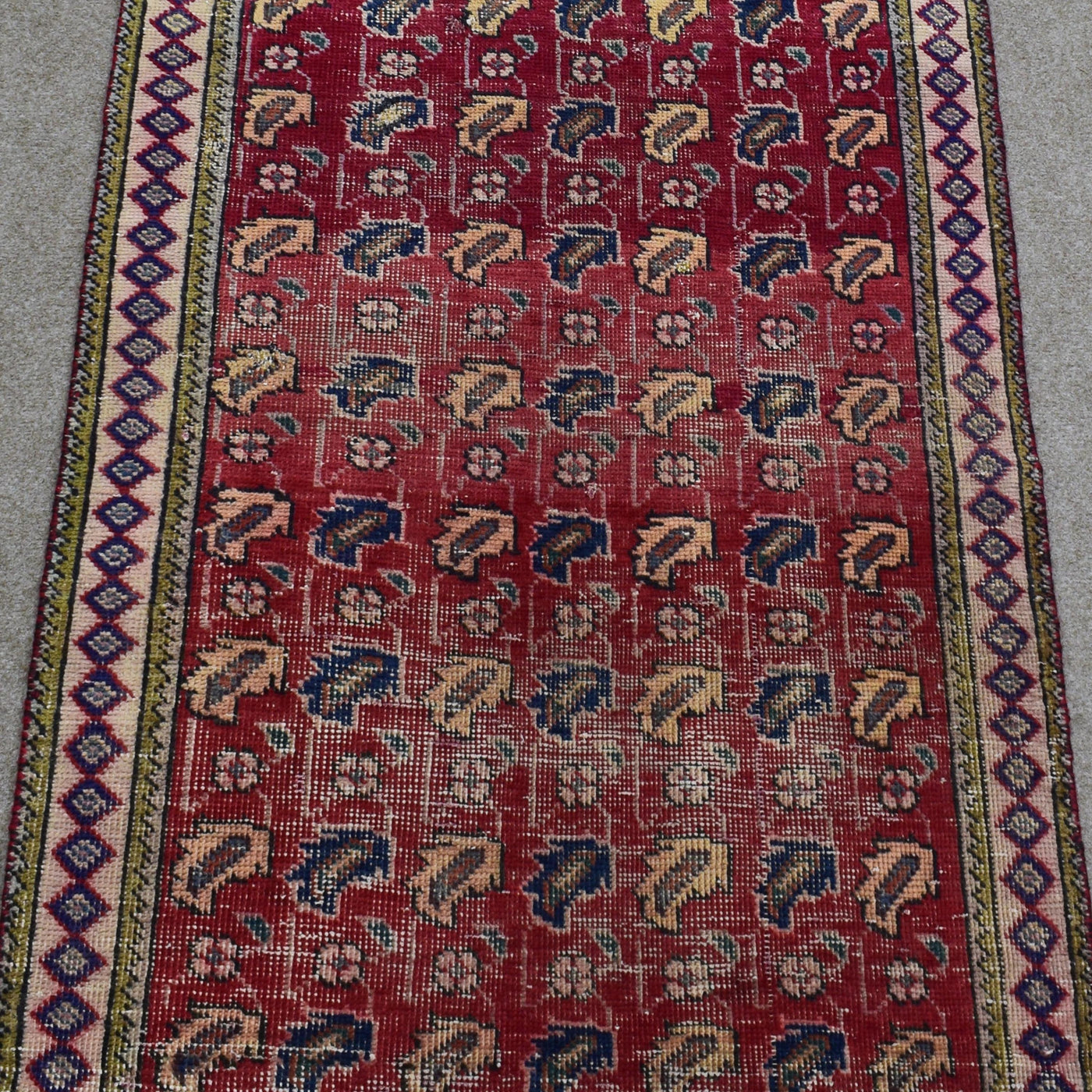 Close view of vintage Shiraz Persian rug showing dense rows of traditional tribal motifs in red, ivory and blue tones