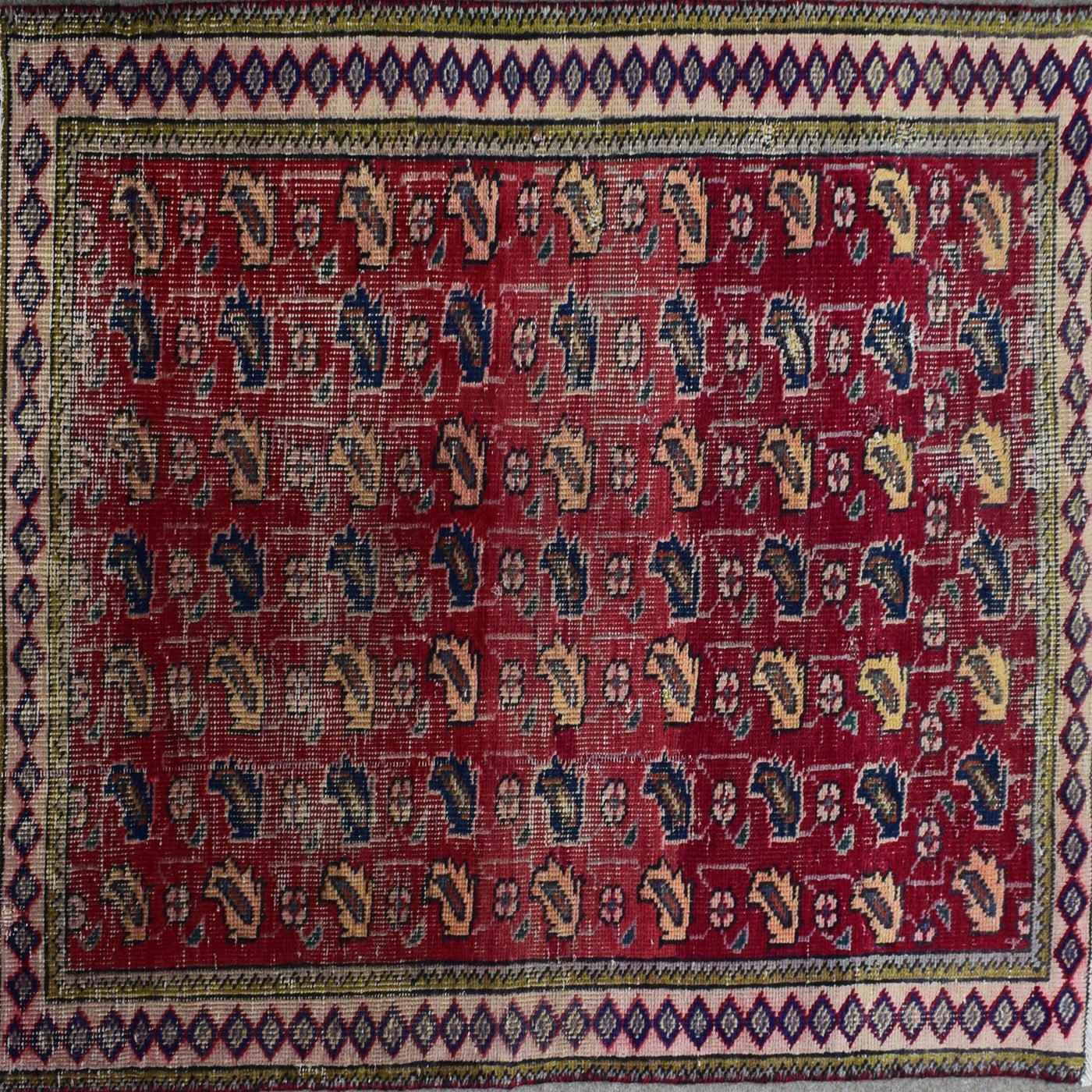 Detailed field of vintage Persian Shiraz rug featuring repeating stylized tribal motifs on rich red background