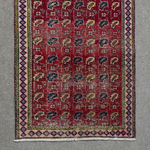 Hand knotted Shiraz rug section showing repeating geometric tribal figures and decorative border on red ground