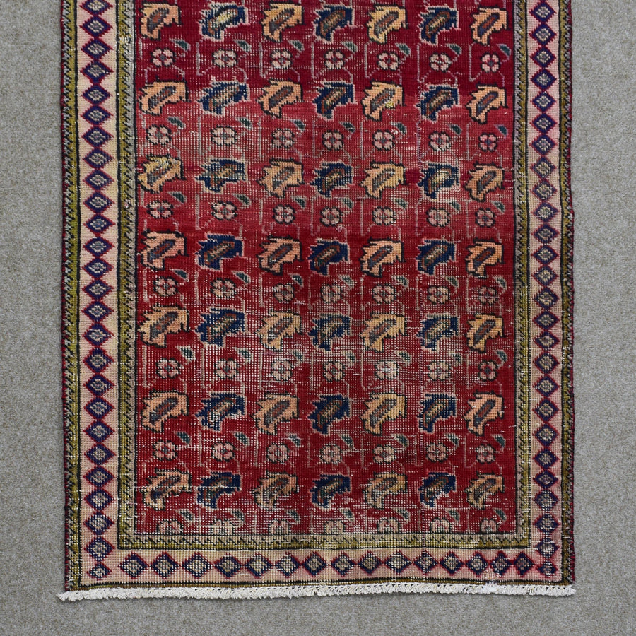 Hand knotted Shiraz rug section showing repeating geometric tribal figures and decorative border on red ground
