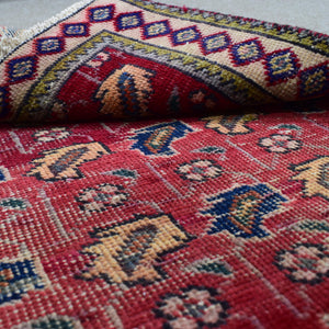 Detailed close up of vintage Shiraz Persian rug showing wool pile with tribal motifs in red, blue, ivory and gold tones