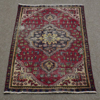 Vintage Persian Shiraz rug 90x137 cm showing central ivory medallion and geometric tribal motifs on deep red background