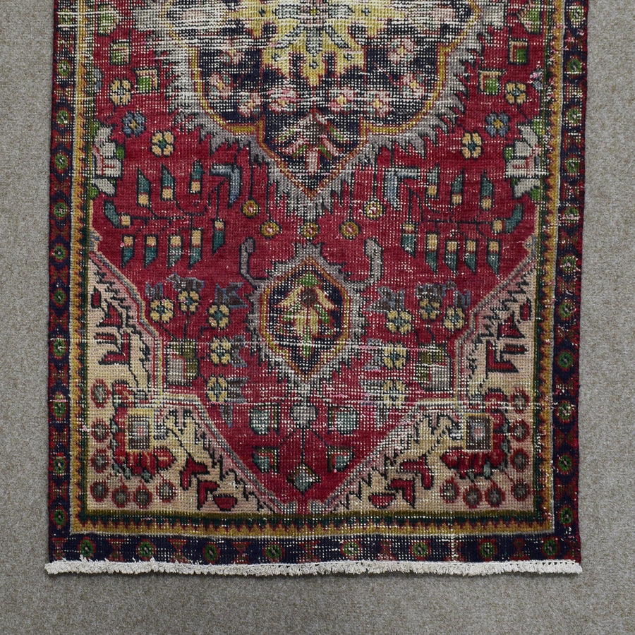 Section of Shiraz Persian rug showing central medallion edge and repeating tribal motifs on red field