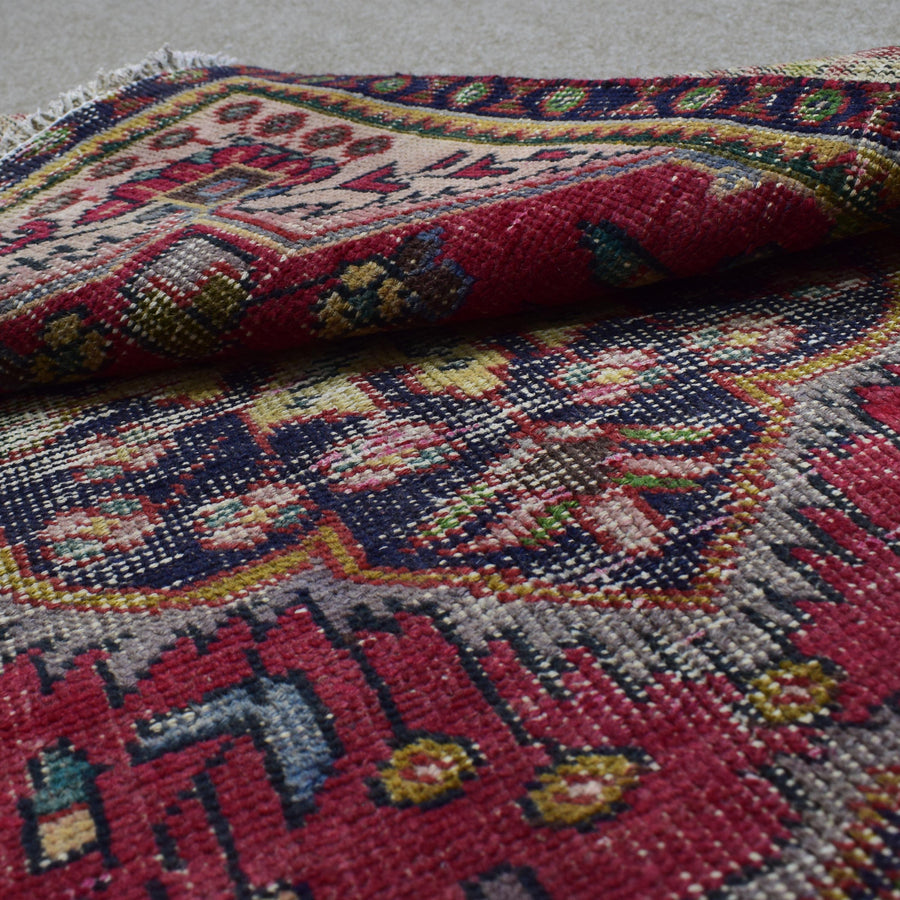Folded edge of vintage Shiraz Persian rug revealing thick wool pile and tribal geometric design
