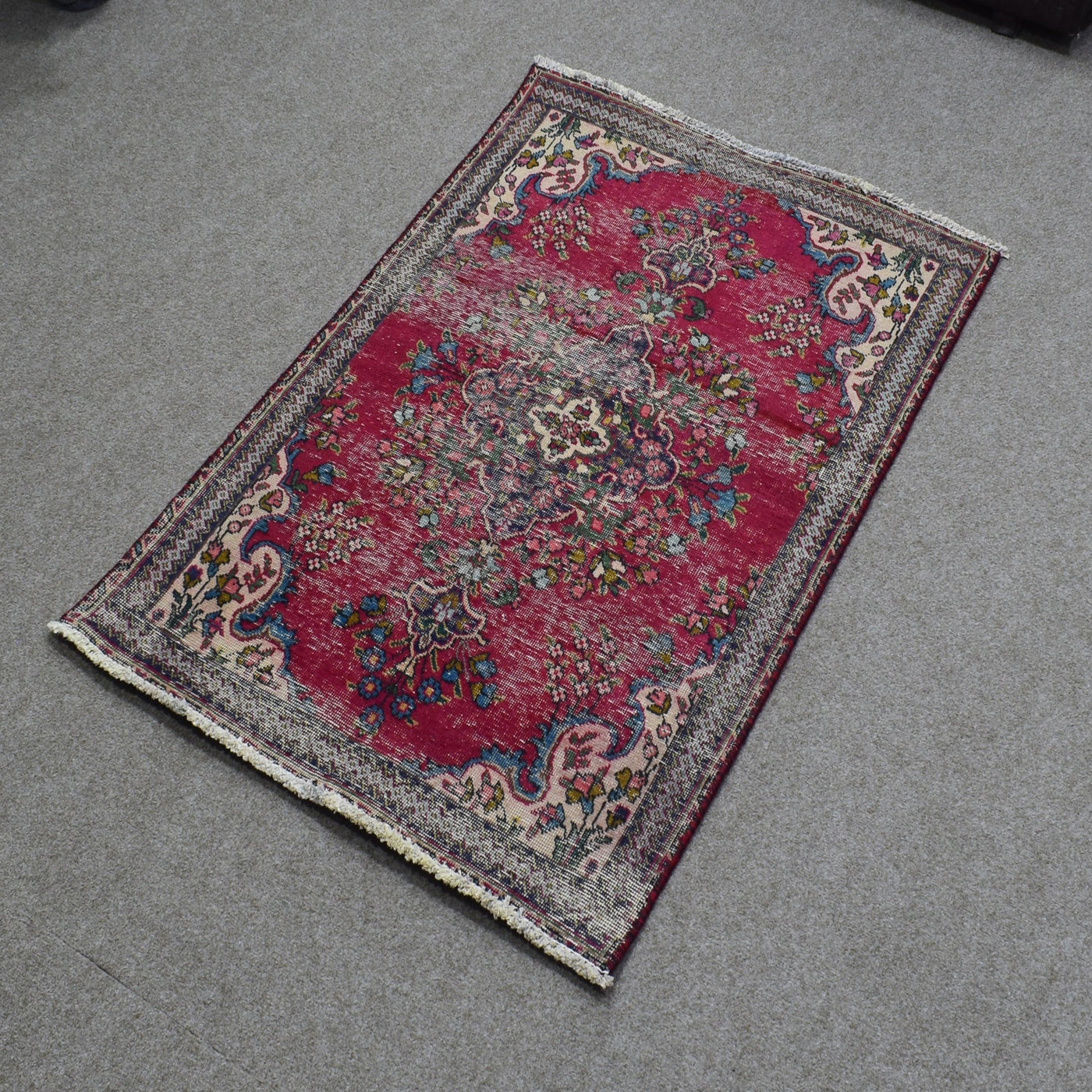 Hand knotted Persian Shiraz rug photographed at an angle featuring central medallion and decorative floral border on red field