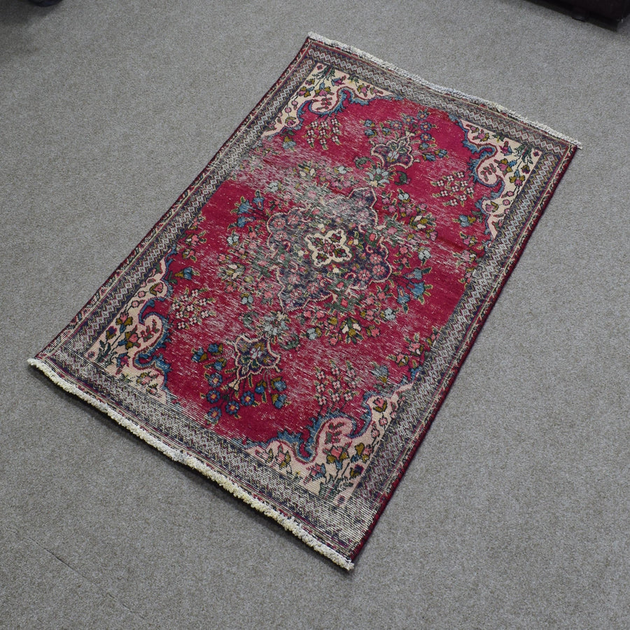 Hand knotted Persian Shiraz rug photographed at an angle featuring central medallion and decorative floral border on red field