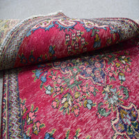 Folded vintage Persian Shiraz rug showing pile height, dense knotting and floral pattern detail