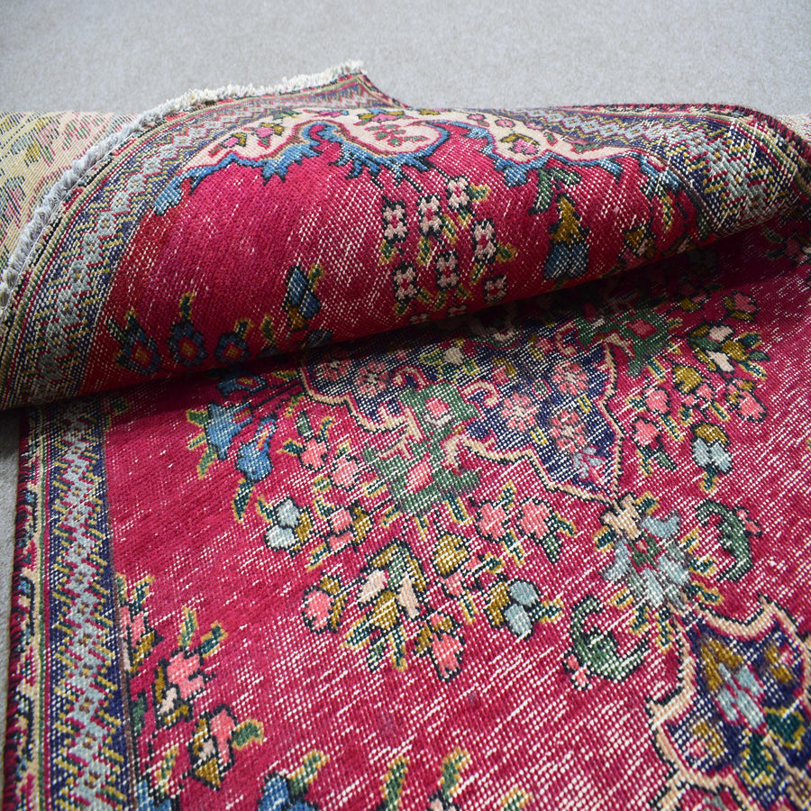 Folded vintage Persian Shiraz rug showing pile height, dense knotting and floral pattern detail