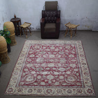 Large distressed vintage Persian rug 290x377 cm styled in interior showing faded red floral design and ivory border