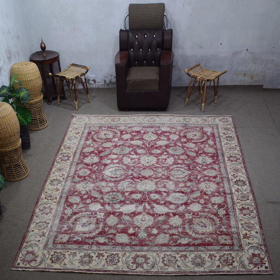 Large distressed vintage Persian rug 290x377 cm styled in interior showing faded red floral design and ivory border