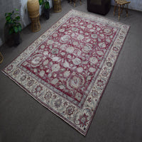 Hand knotted Persian rug photographed at an angle showing large faded floral pattern and decorative border